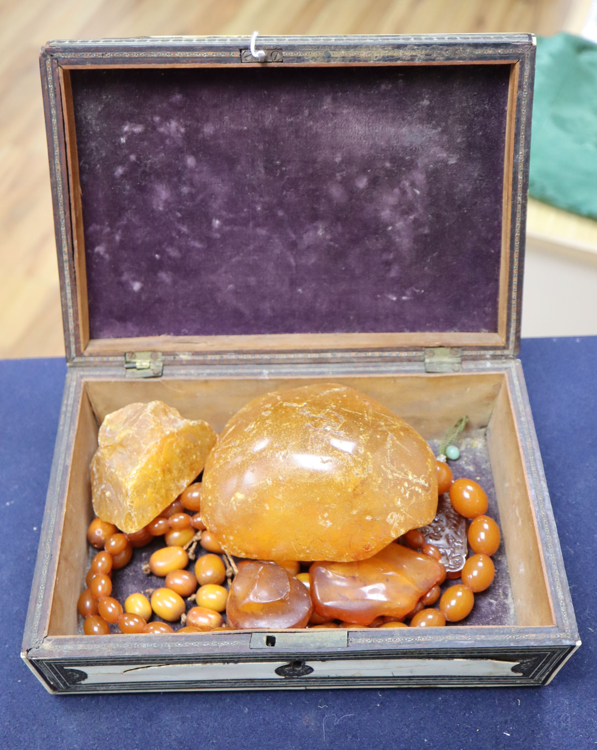 An amber necklace(a.f.) gross 85 grams, four assorted amber pebbles, 528 grams, a carved amber pendant